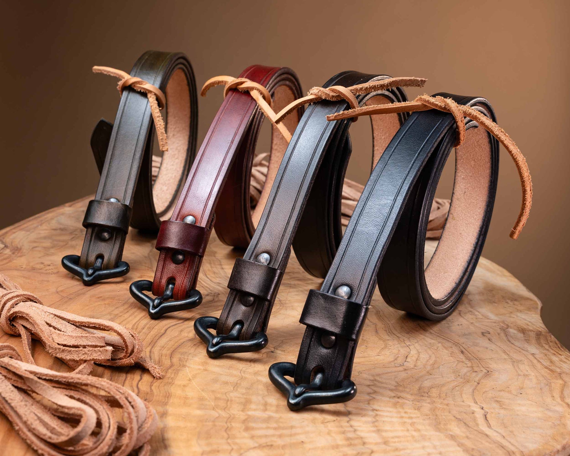 Assortment of authentic medieval leather belts in various colors, showcasing the hand-finished leather straps and period-accurate black metal hardware.