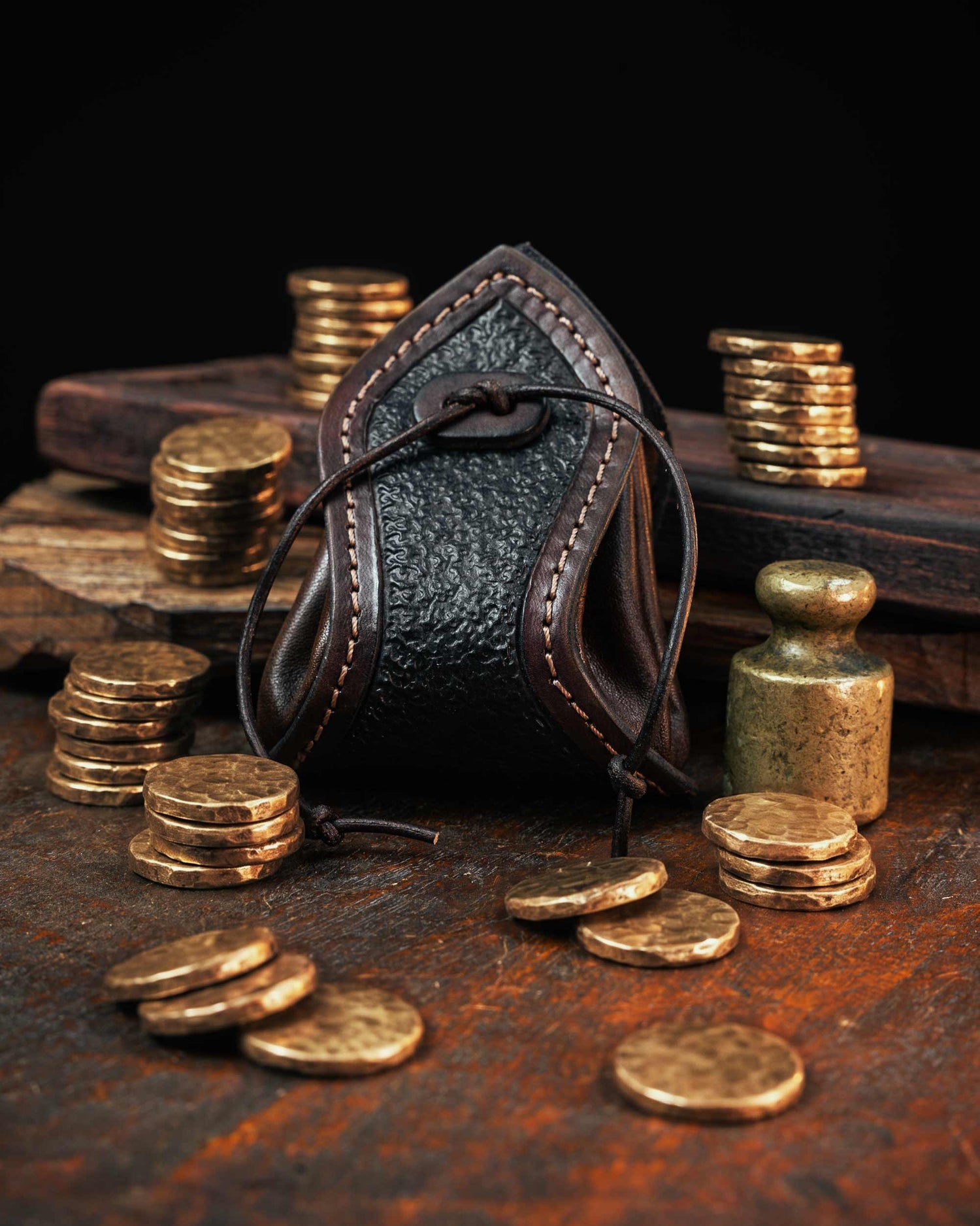Dark brown handmade leather coin pouch featuring a textured front panel and stitched edges, secured with a custom leather drawstring.