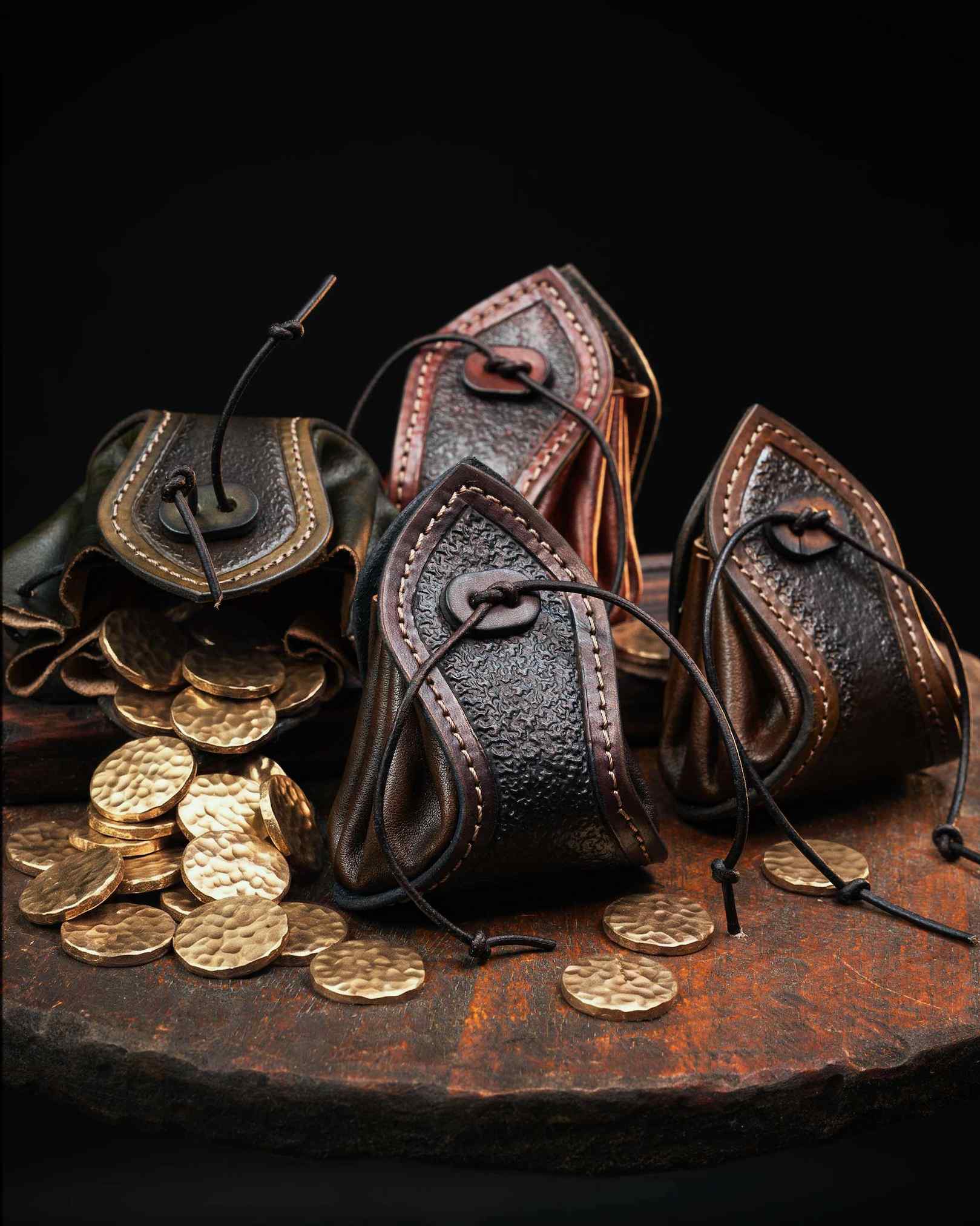 Open handcrafted leather coin pouch with a custom drawstring closure, spilling hammered brass coins, ideal for LARP or as a tabletop RPG dice bag.
