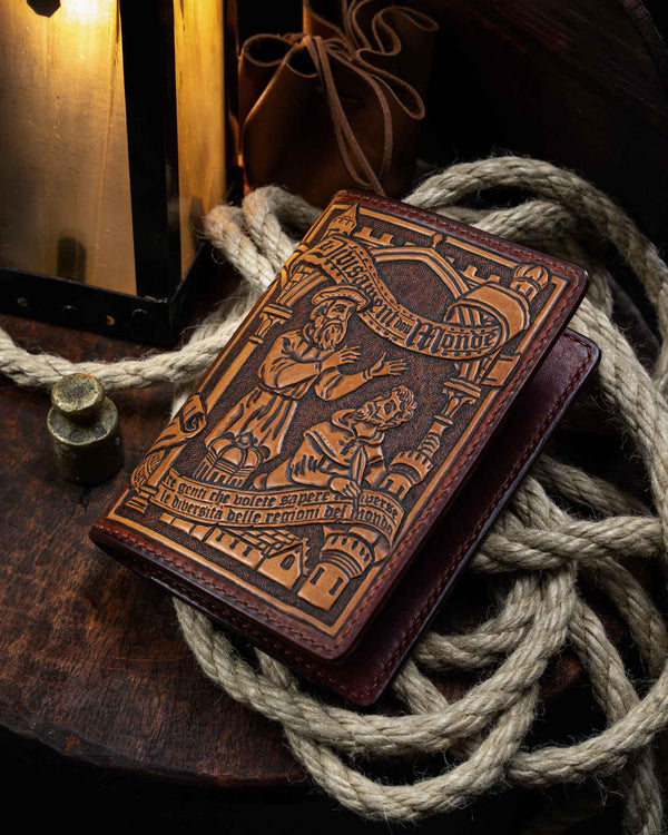 Angled close-up of the handcrafted Marco Polo leather passport wallet, highlighting the depth of the 3D tooling, the text banner, and the dark burnished edges.