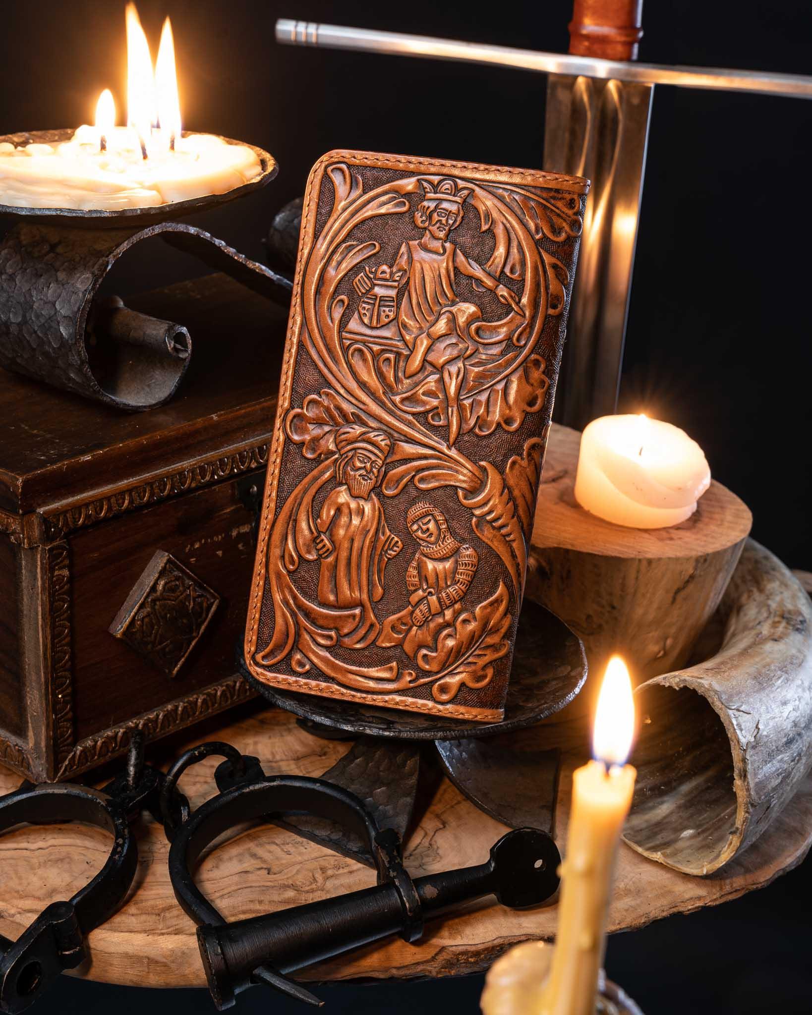 Back view of the artisan leather long wallet, showcasing continuous hand-tooled medieval characters and floral scrollwork against a dark textured background.