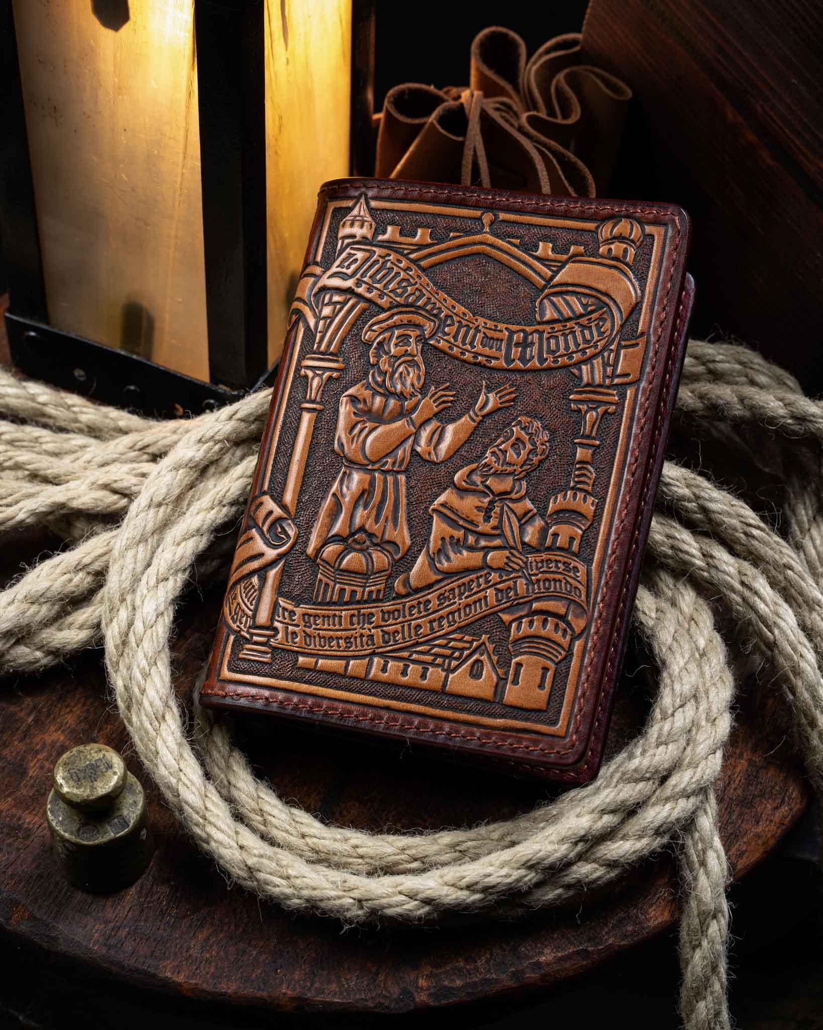Handcrafted leather passport wallet featuring an intricate hand-tooled medieval scene inspired by Marco Polo's Devisement du Monde, resting on nautical ropes.