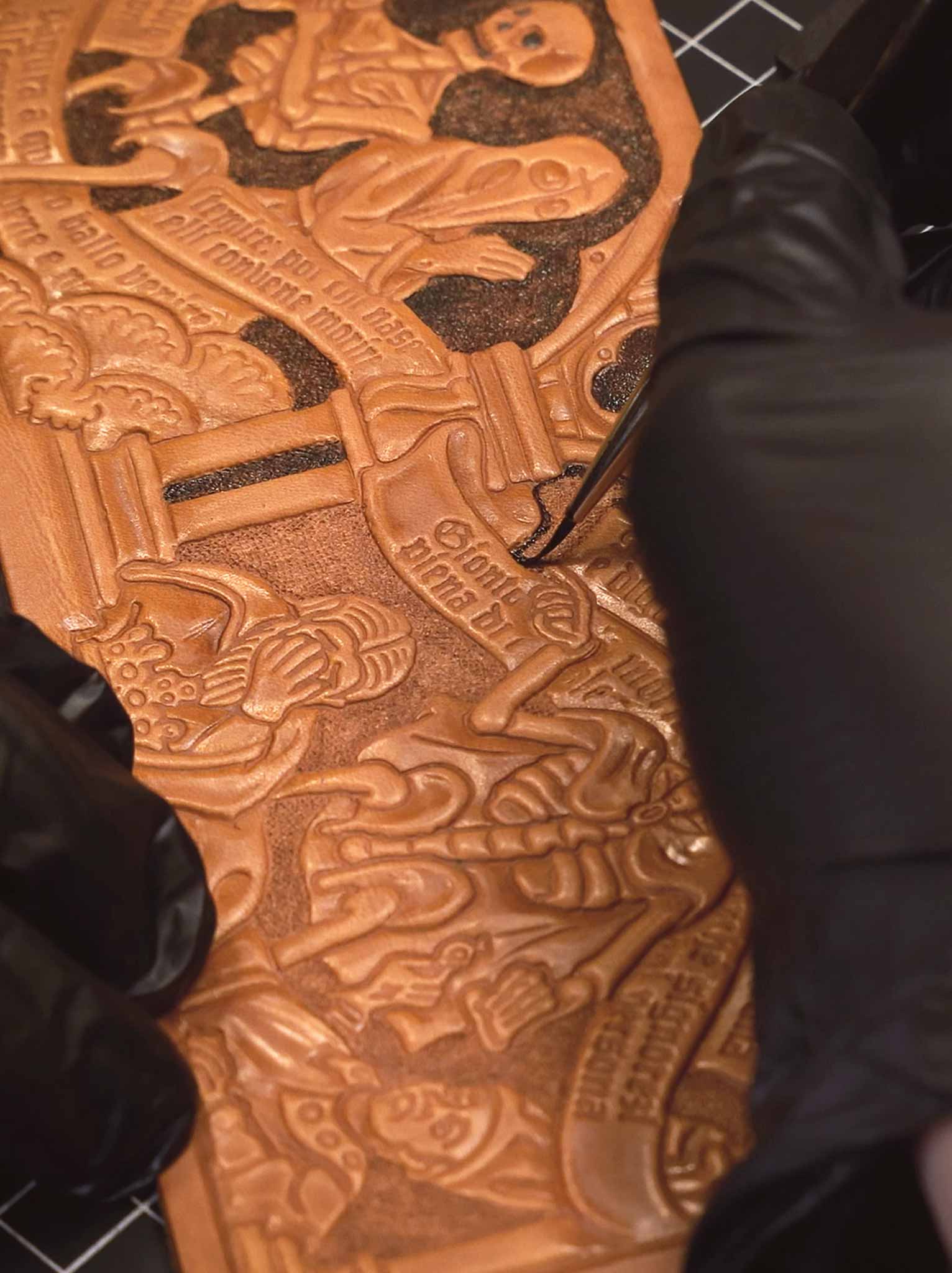 Michele Belvedere hand-painting the Trionfo della Morte wallet for Reliq. Medieval-inspired tooling on vegetable-tanned leather, finished with dark tones to enhance the details.