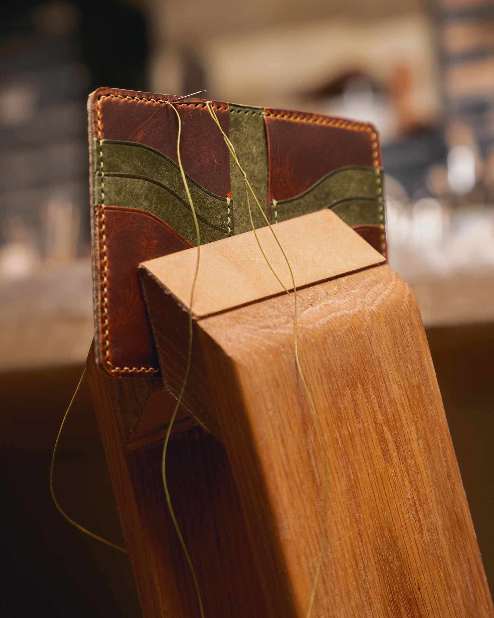 Reliq Leather handmade wallet in vegetable-tanned leather being stitched by hand with saddle stitch, showing artisanal process and traditional craftsmanship.