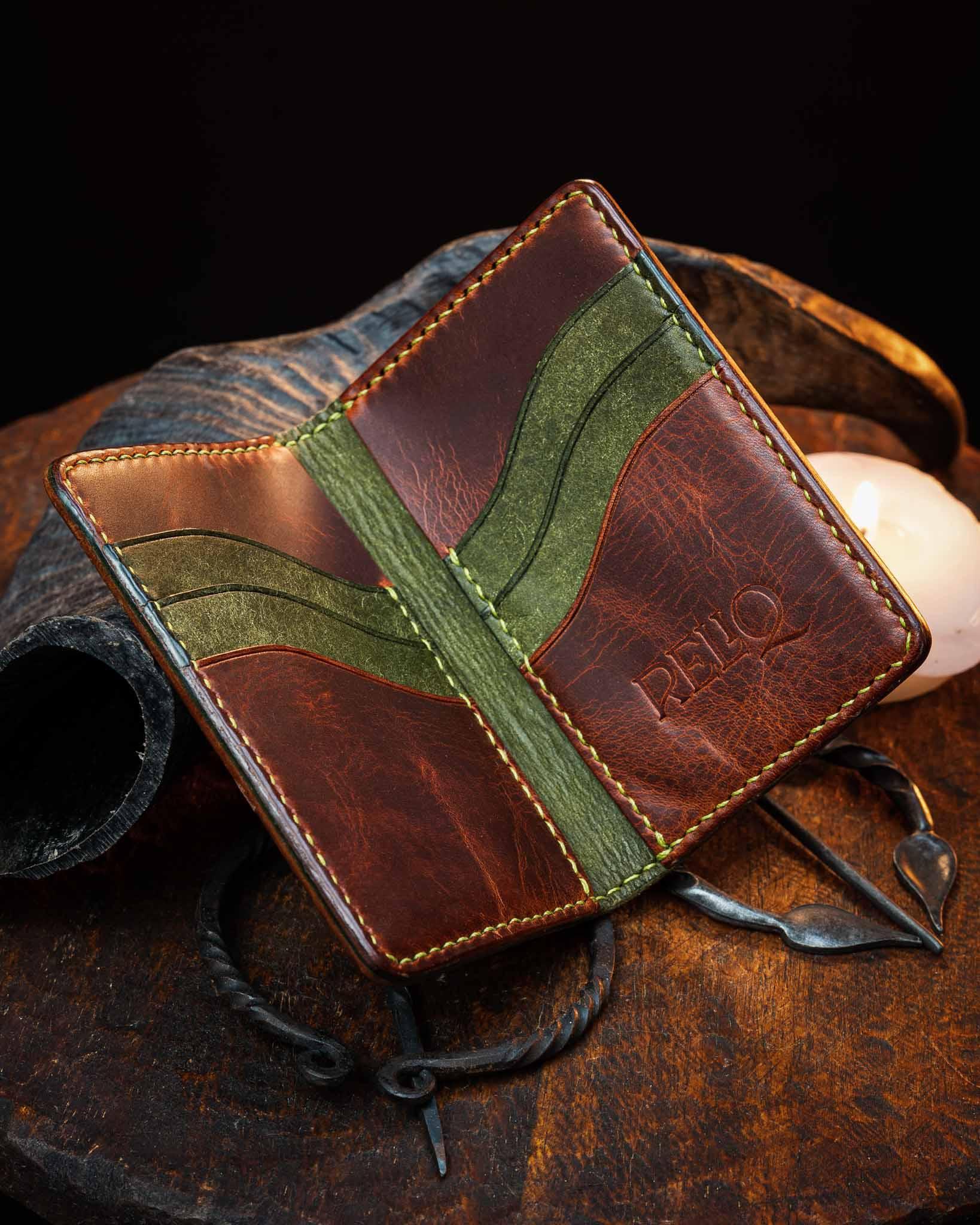Open artisan leather wallet revealing a two-tone interior with brown and green genuine leather card slots, detailed with precise saddle stitching.