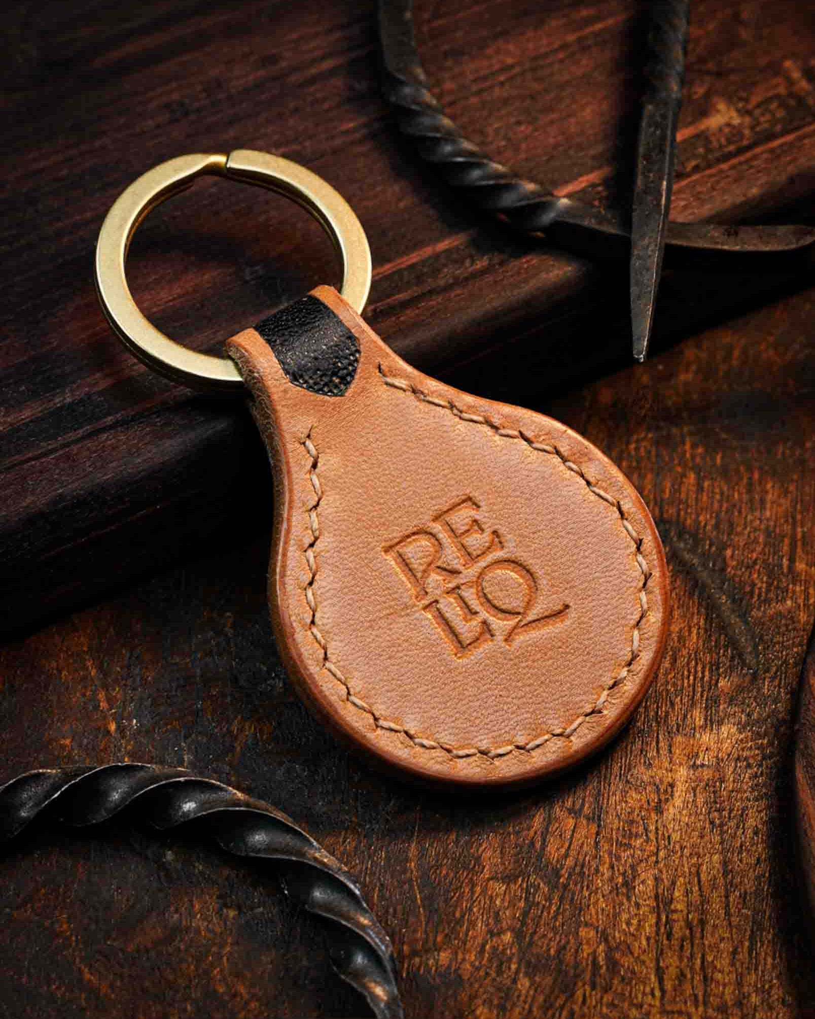Back view of a handmade leather keyring showcasing smooth tanned leather, detailed edge saddle stitching, and the stamped Reliq workshop logo.
