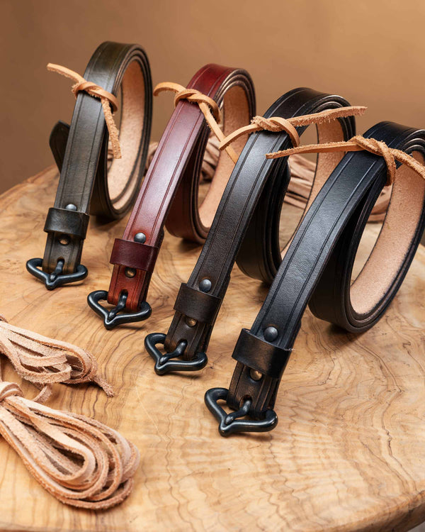 Close-up view of the period-accurate black metal buckles and riveted strap attachments on four handcrafted medieval leather belts.