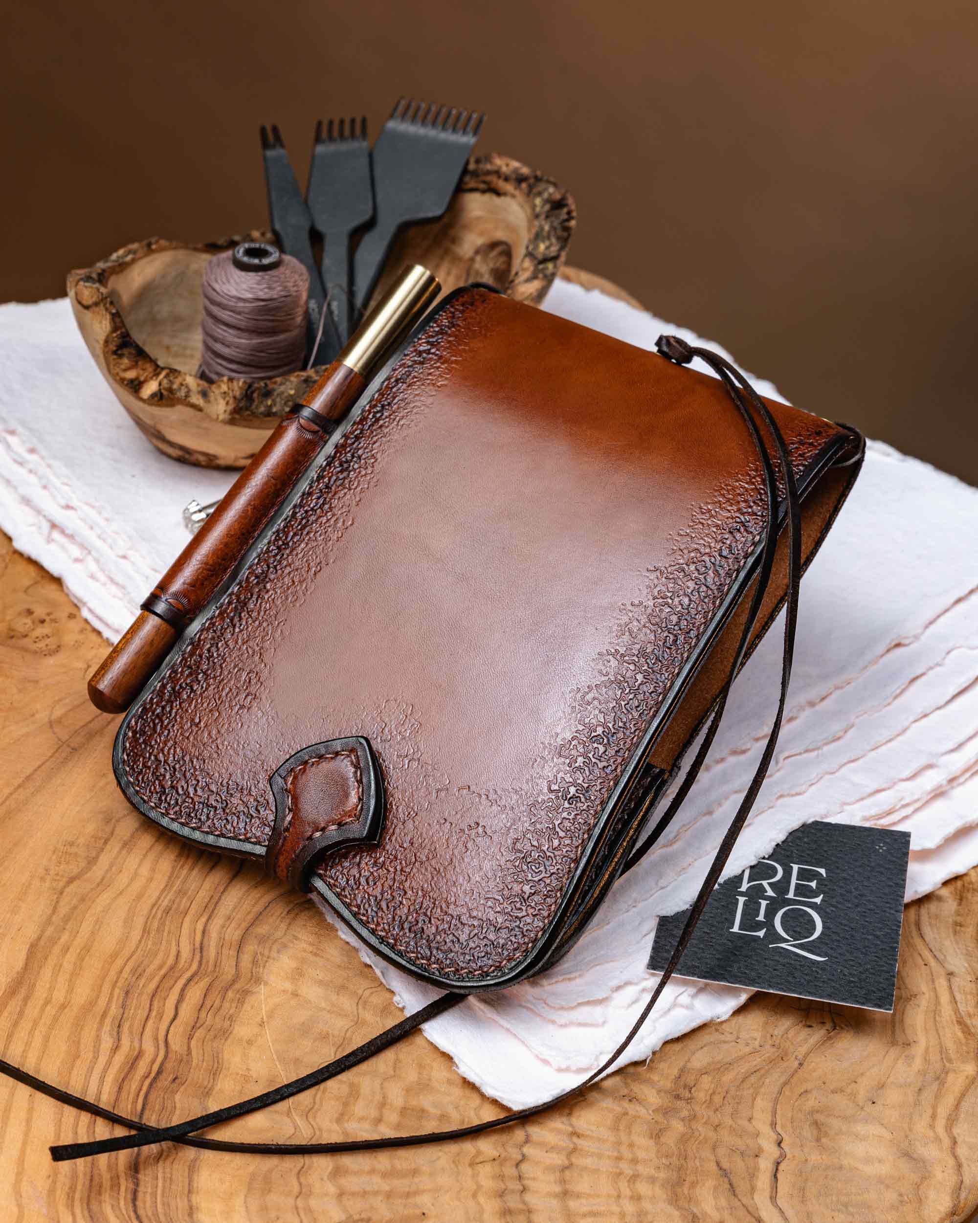 Back view of a handmade brown leather A6 journal cover, highlighting the smooth central finish, textured dark borders, and saddle-stitched details.
