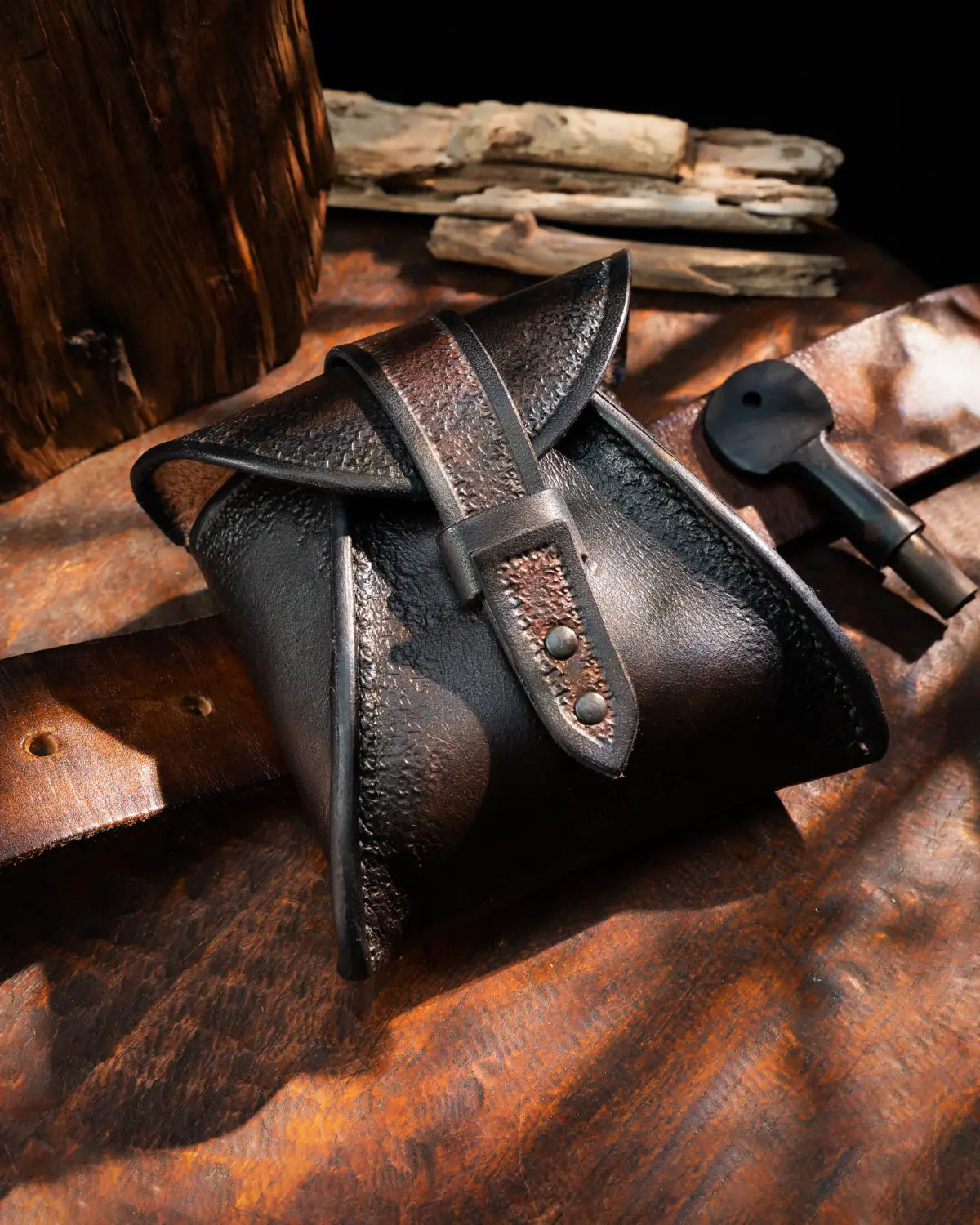 Black hand-tooled small leather pouch with dark brown undertones and friction-lock belt strap loop