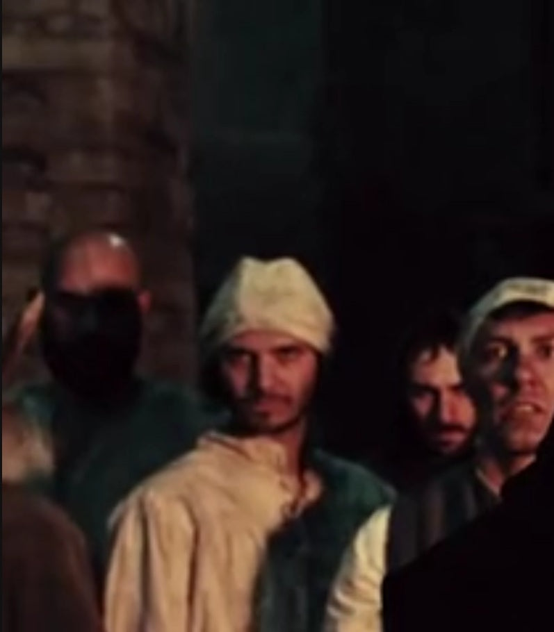 Close-up cinematic still from the 2020 film Curse of the Blind Dead, featuring a background actor in medieval peasant clothing, highlighting authentic on-set scenic presence