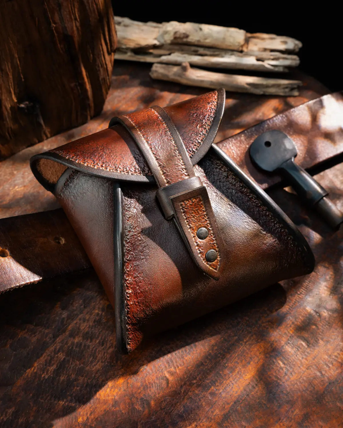 Brown hand-tooled vegetable-tanned leather belt pouch with buttonless loop closure on a waist belt