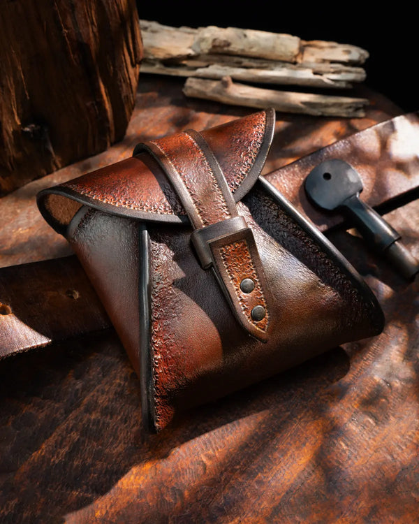 Brown hand-tooled vegetable-tanned leather belt pouch with buttonless loop closure on a waist belt