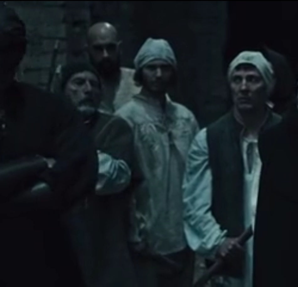 A cinematic still from the 2020 movie Curse of the Blind Dead, showing a group of background actors in medieval costumes in a dimly lit setting, showcasing professional experience as a film extra