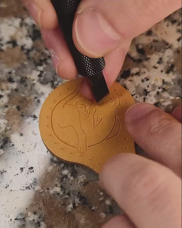 Making of the medieval marginalia cat leather keyring: close-up of hand-tooling the historical manuscript illustration using a swivel knife and beveler.