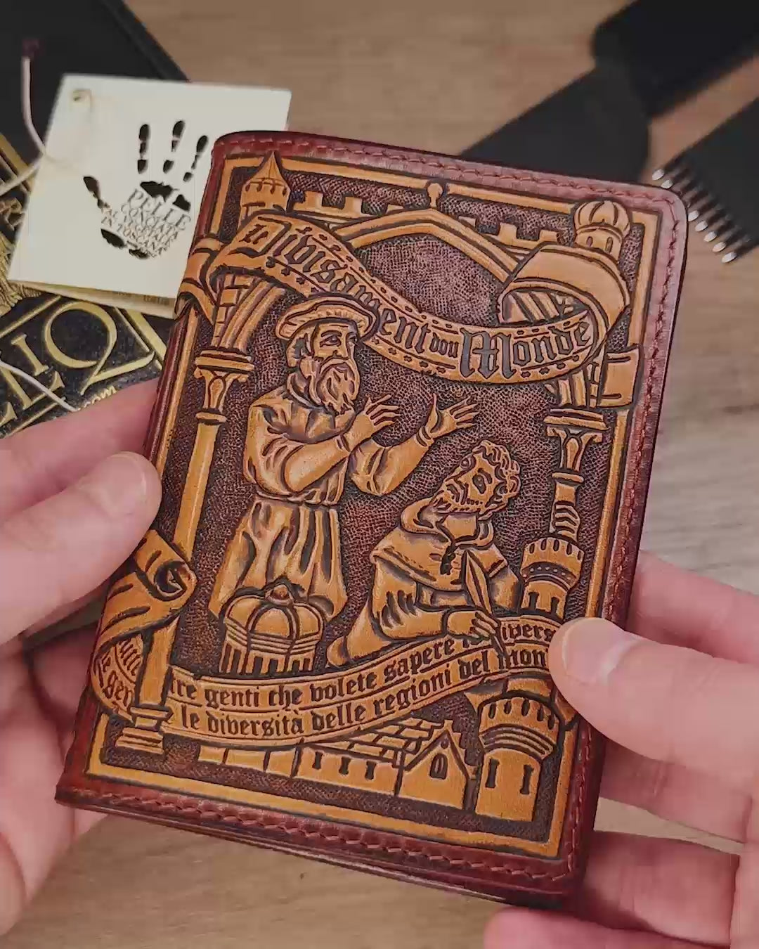 Video preview showing the artisan holding the finished hand-tooled Marco Polo leather passport cover, highlighting its real-world scale and detailed craftsmanship.