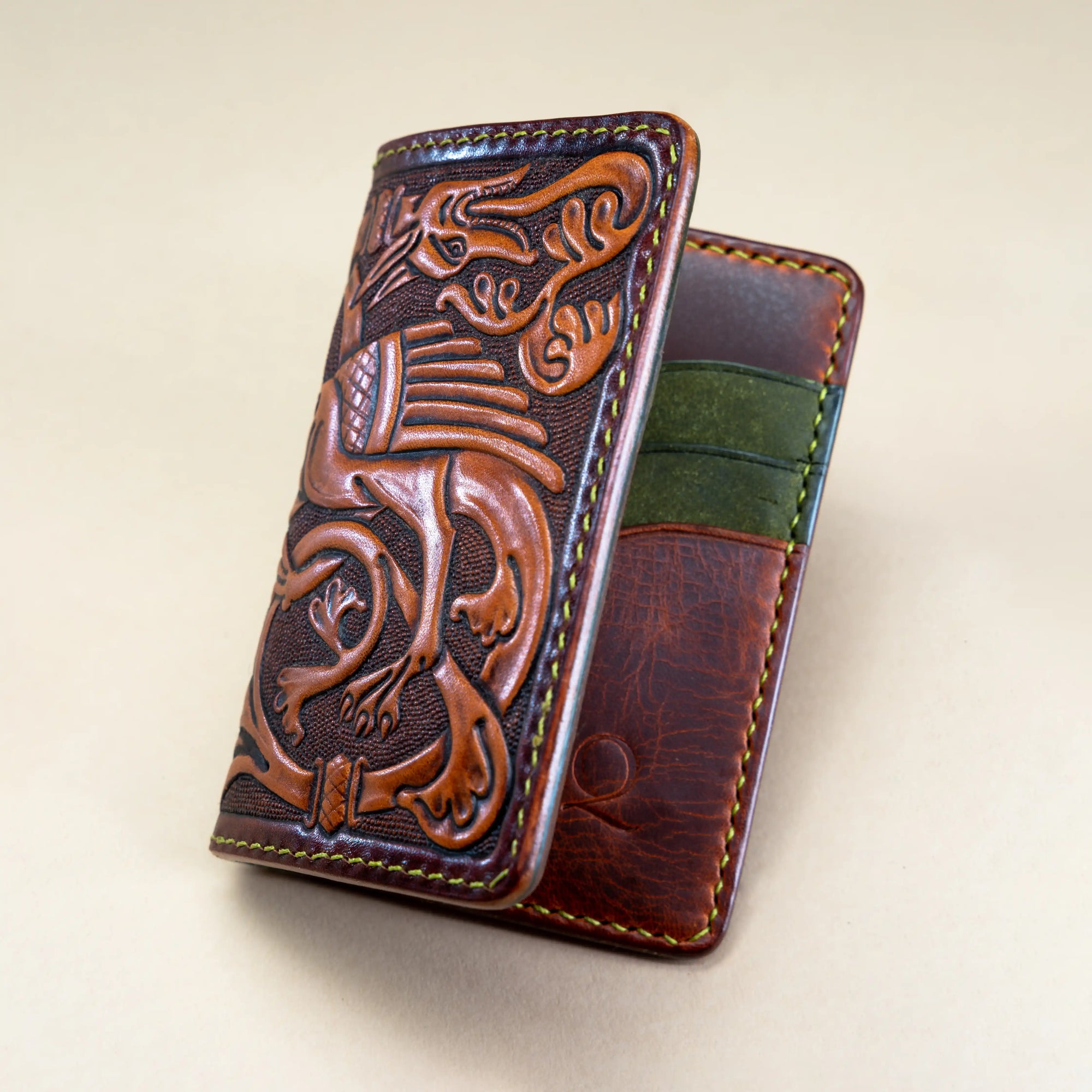 Hand-tooled leather card holder wallet featuring a medieval Western dragon motif, inspired by 12th-century illuminated bestiaries. Reliq artisanal craftsmanship, mahogany exterior with green interior.