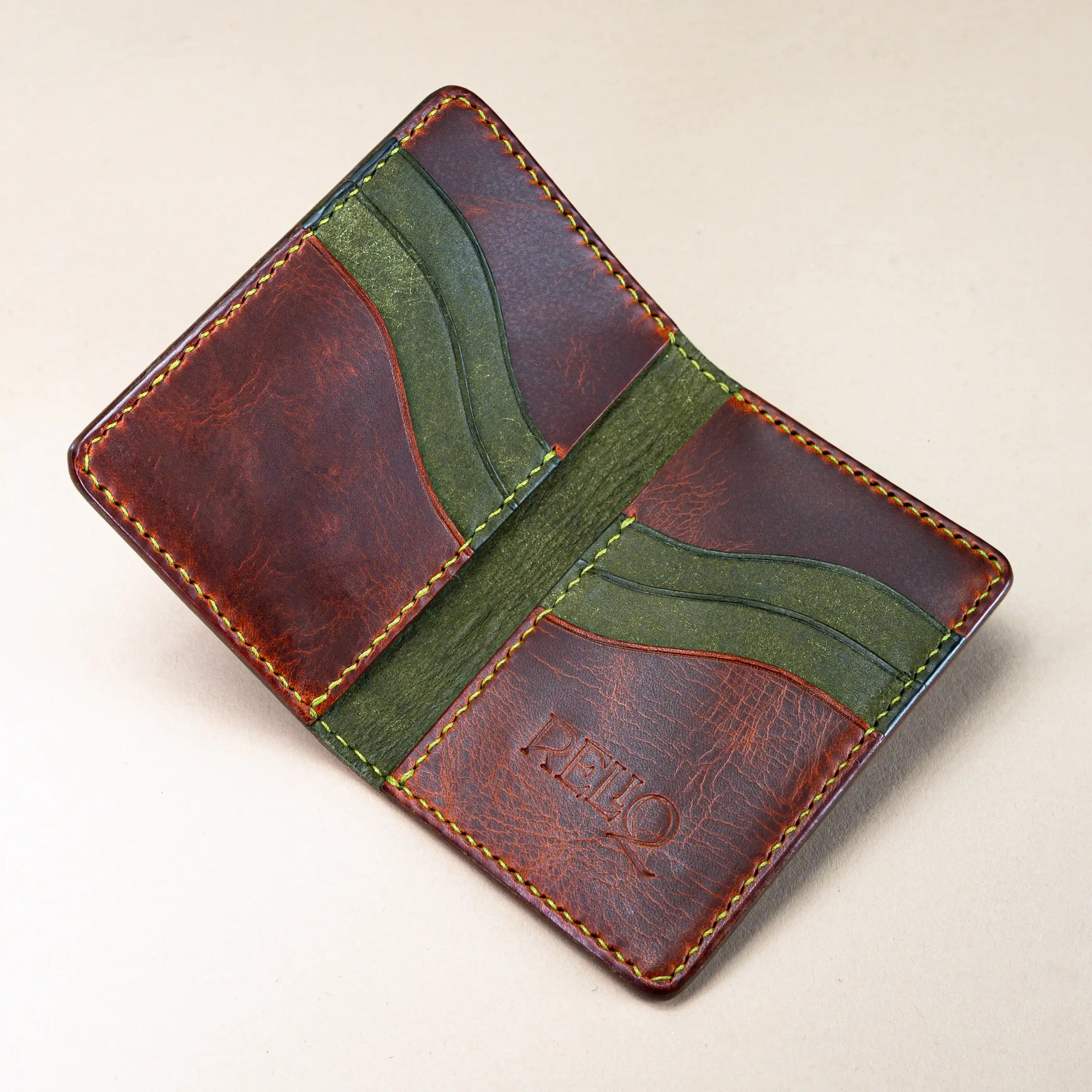 Western Dragon leather card holder wallet opened to reveal six card slots and two compartments, in contrasting mahogany and green Italian vegetable-tanned leather.