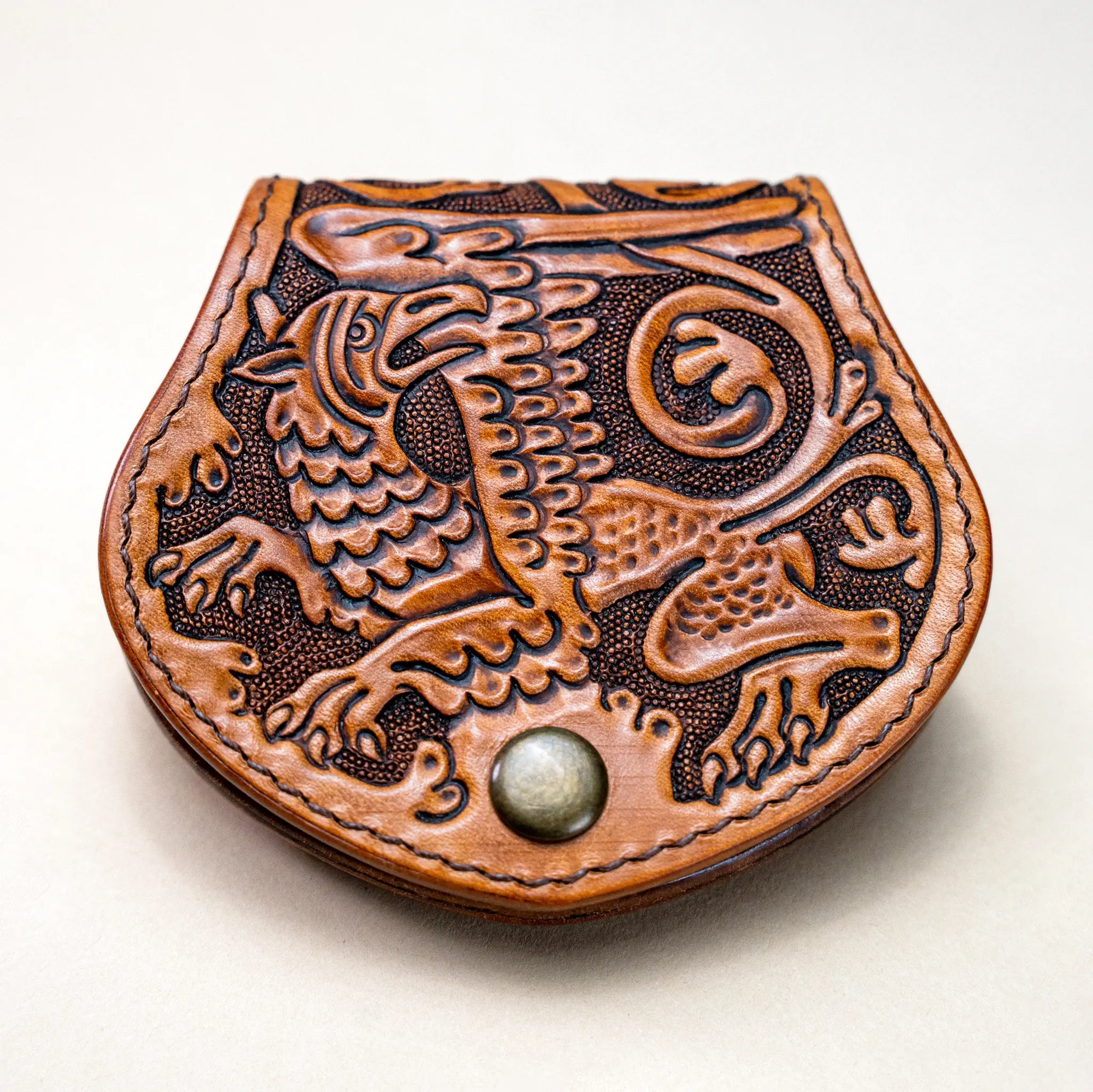 Hand-tooled leather coin purse featuring a medieval gryphon motif, inspired by medieval bestiaries. Reliq Leather handmade wallet, natural honey finish.