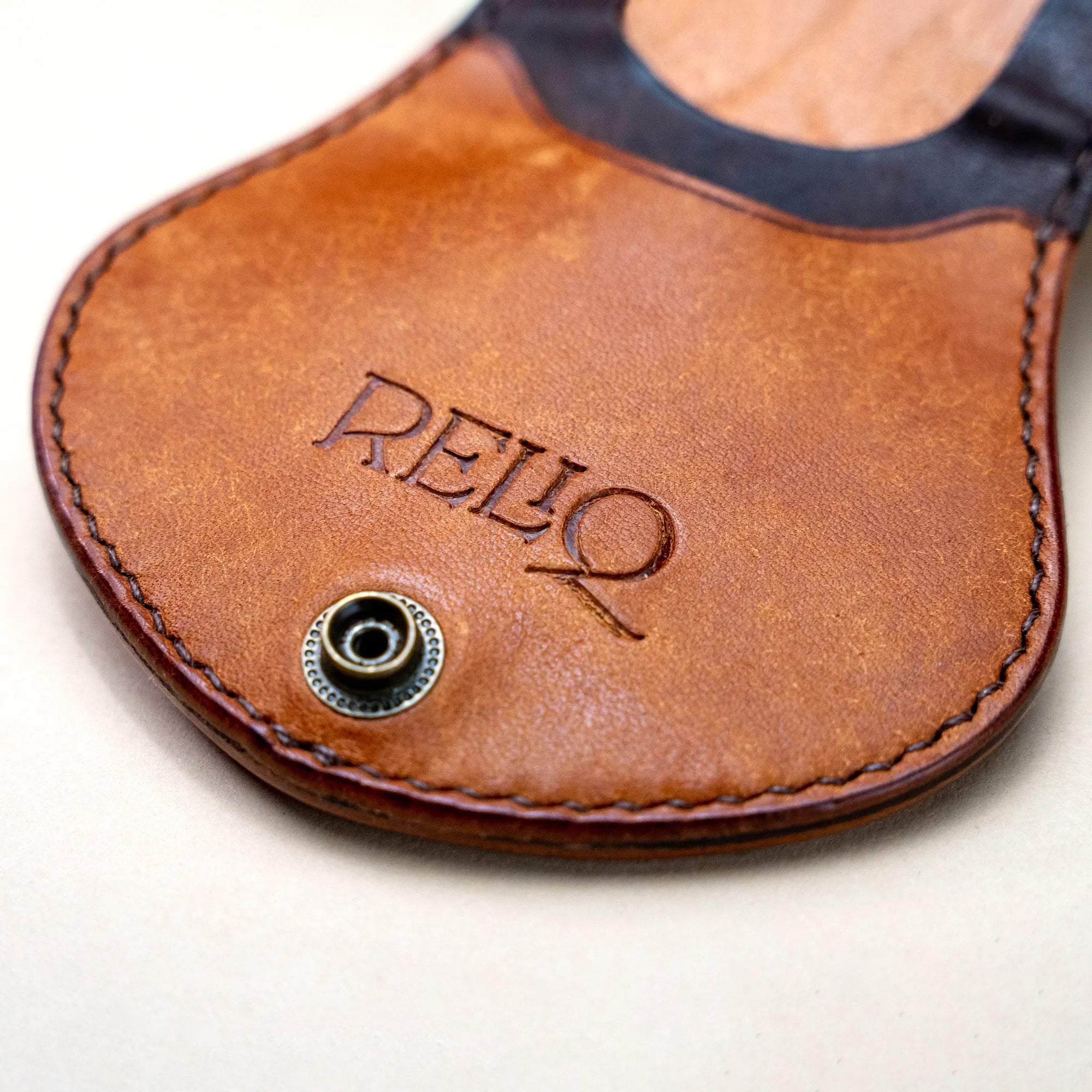 Close-up of Reliq Leather embossed logo on Gryphon handmade coin purse in Italian vegetable-tanned leather.
