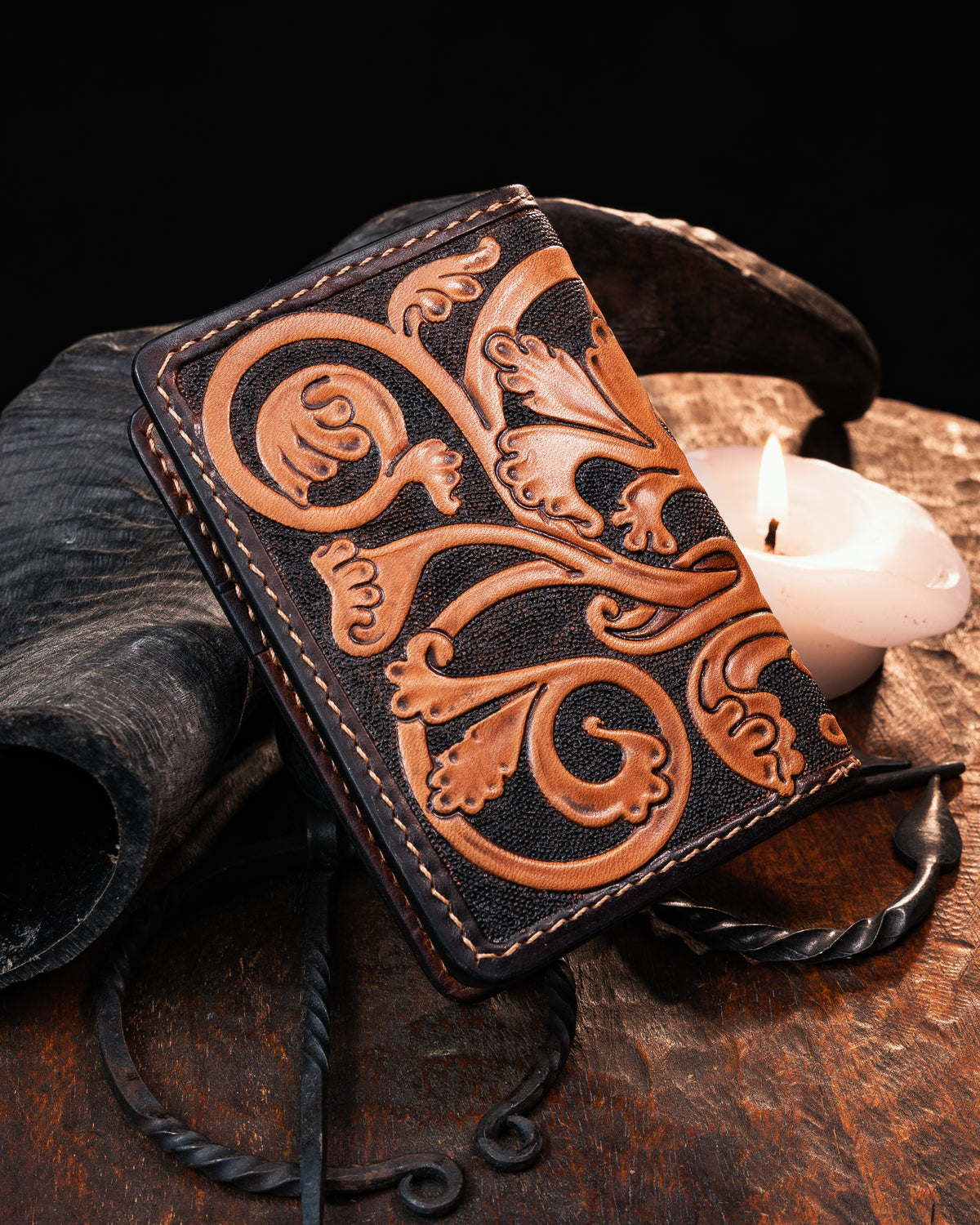 Back view of a medieval leather card holder showcasing intricate hand-carved foliate marginalia scrollwork. Hand-tooled artisan wallet with illuminated manuscript details.